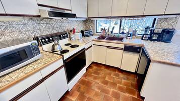 A kitchen with white cabinets, a microwave, stove, toaster, and a dishwasher.