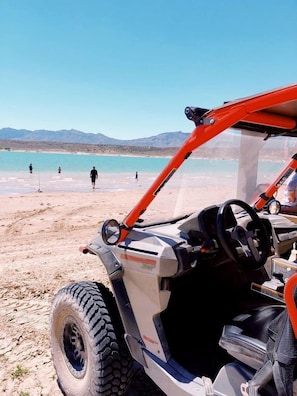 Un vehículo en la playa con vista despejada a la playa y montañas al fondo.
