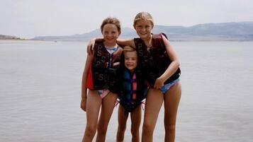Four people standing in shallow water with a clear sky and distant mountains in the background.