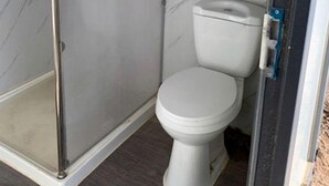 A bathroom with a toilet, a shower enclosure, and a wall-mounted air conditioning unit. - Spacious Pet-Friendly Safari Tent on Yuba Lake with Spectacular Views for a Memorable Glamping Escape in Utah (Levan)