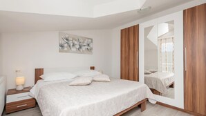Une chambre à coucher avec un lit, une table de chevet, une lampe et un grand miroir.