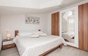 Ein Schlafzimmer mit Bett, Nachttisch, Lampe und einem großen Spiegel.