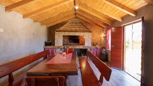 Un intérieur rustique avec une cheminée en pierre, des poutres en bois et un coin repas avec des bancs.