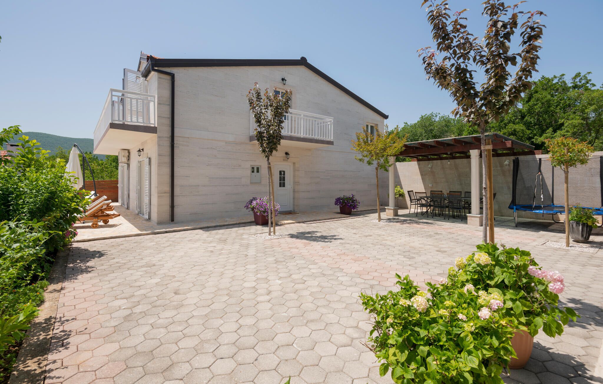 A modern building with a hexagonal tile courtyard, outdoor seating, and potted plants.