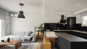 Une cuisine moderne dotée d’un îlot central, d’un coin repas avec un banc et d’un espace de vie comprenant un canapé et une table basse.