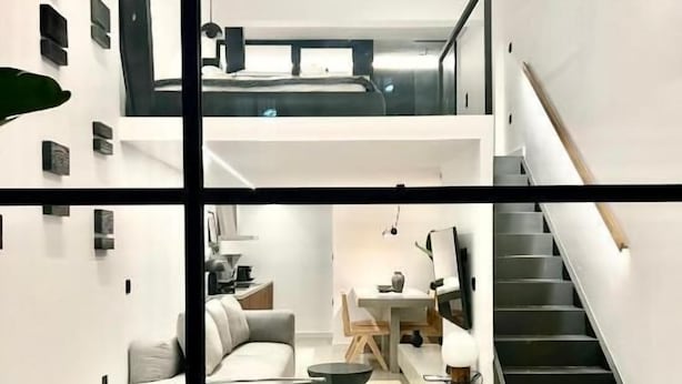 Un intérieur moderne comprenant un escalier, un canapé, un coin repas et un téléviseur à écran plat.