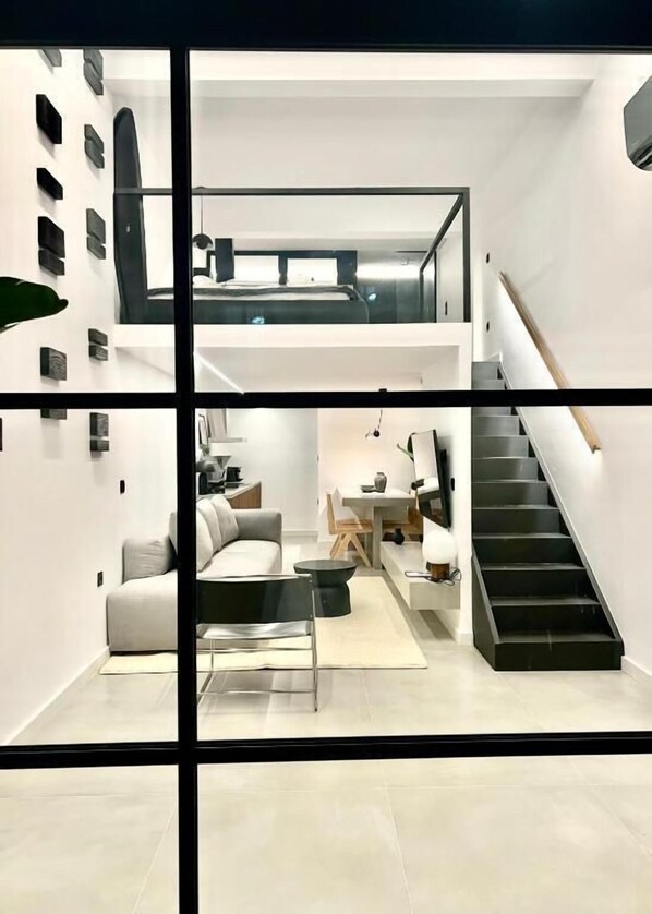 Ein modernes Interieur mit Treppe, einer Couch, einem Essbereich und einem Flachbildfernseher.