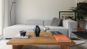 Un salon moderne avec une table basse en bois, des livres, un vase et un canapé.