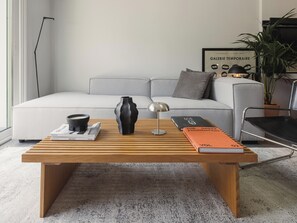 Ein modernes Wohnzimmer mit einem Holztisch, Büchern, einer Vase und einem Sofa.
