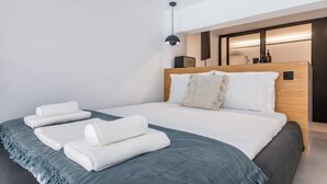 Une chambre d’hôtel moderne avec un grand lit, une tête de lit en bois et une table de chevet avec une lampe.