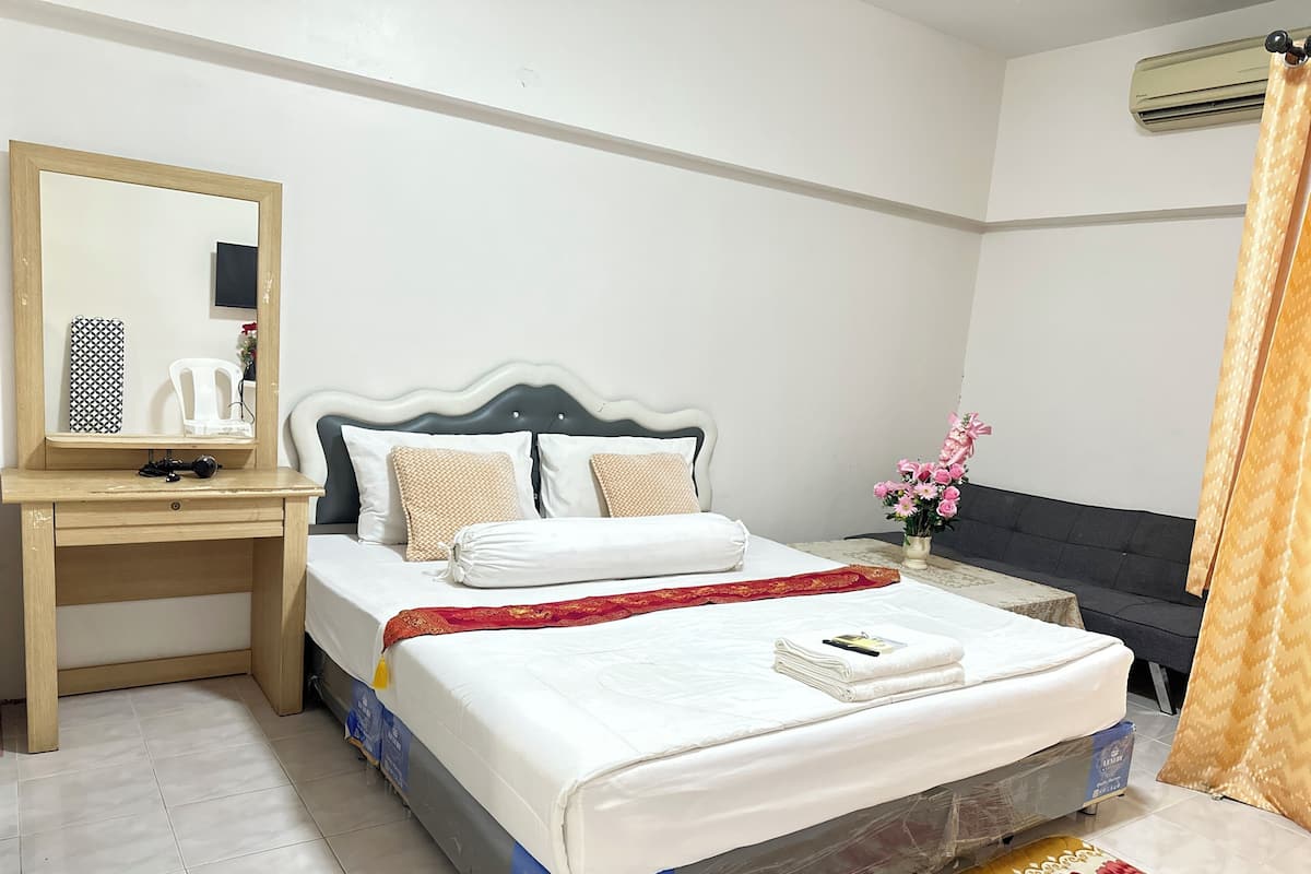 A neatly arranged hotel room with a bed, bedside table, mirror, and a small desk.