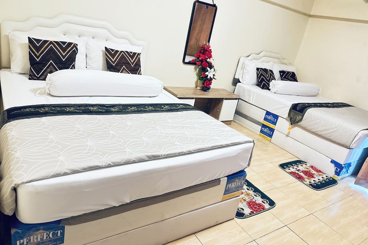 Une chambre dâhĂŽtel avec deux lits, une table de chevet, un miroir et un arrangement floral.