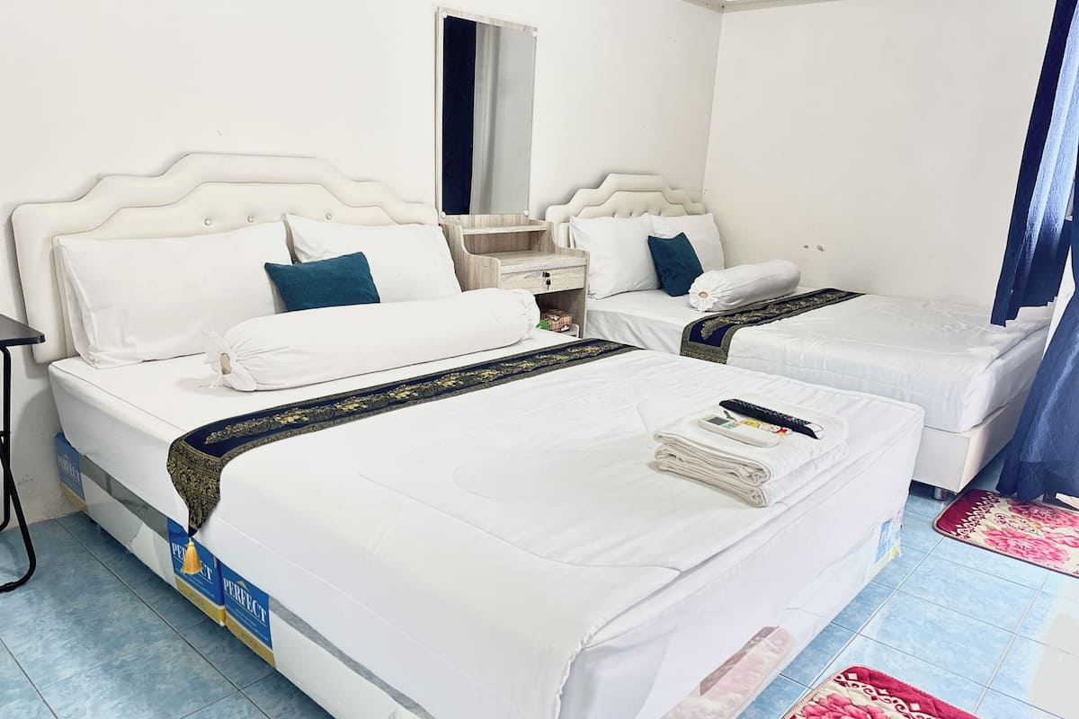 A hotel room with two beds, a nightstand, a mirror, and a red floral rug.