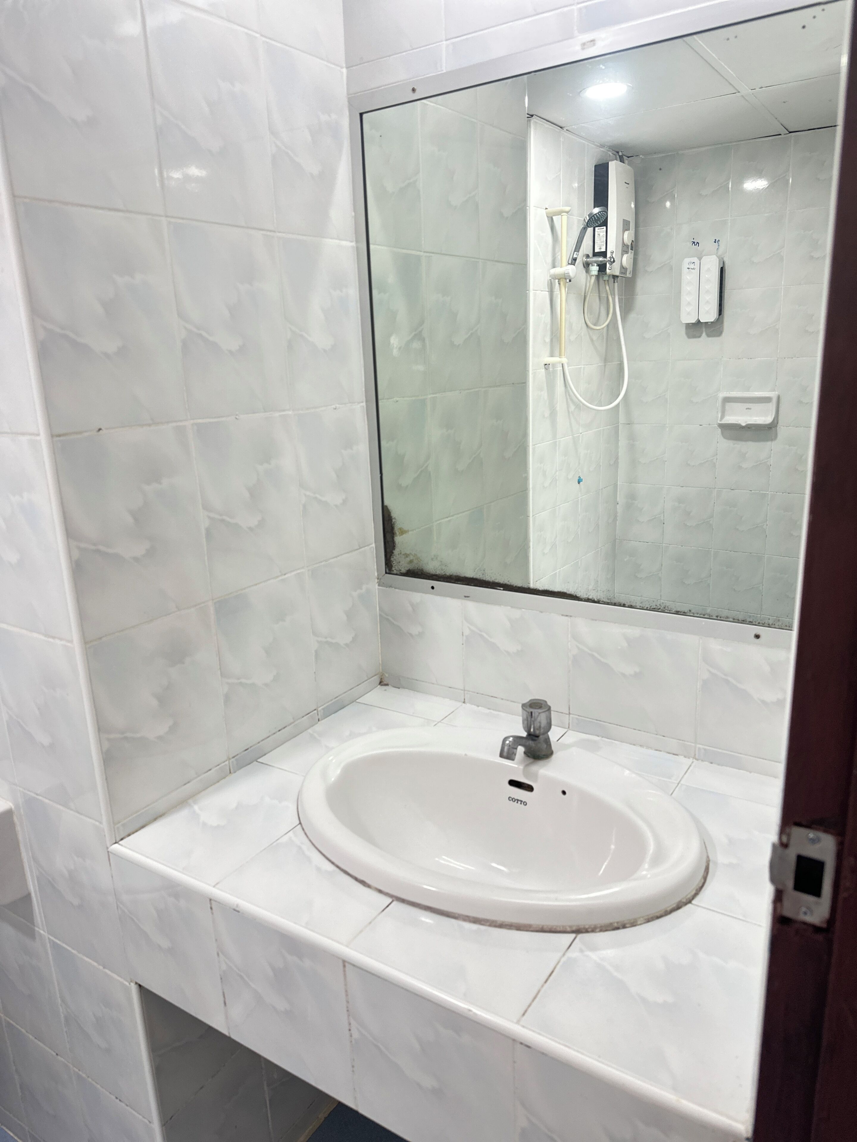 A bathroom with white marble tiles, a white sink, and a mirror.