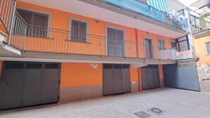 A two-story building with orange walls, grey shutters, and a metal balcony railing. - Cirillo House Marigliano (Marigliano)