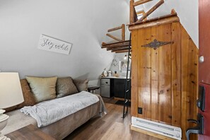 Une pièce confortable avec un lit, une armoire en bois, un bureau et un panneau fixé au mur.