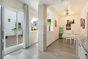Een moderne keuken met een eethoek, een schuifdeur naar een balkon en een hangplant.