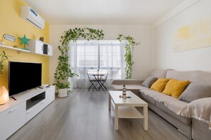 Een woonkamer met een televisie, bank, salontafel en een balkon met uitzicht.