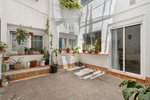 A courtyard with potted plants, a tiled floor, and a large sliding glass door.