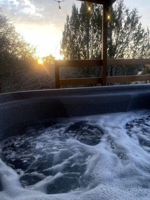 A hot tub with a wooden deck and a view of trees and the sky. - Vacation Cabin Rental with a Private Hot Tub near Fort Worth, Texas (Bluff Dale)