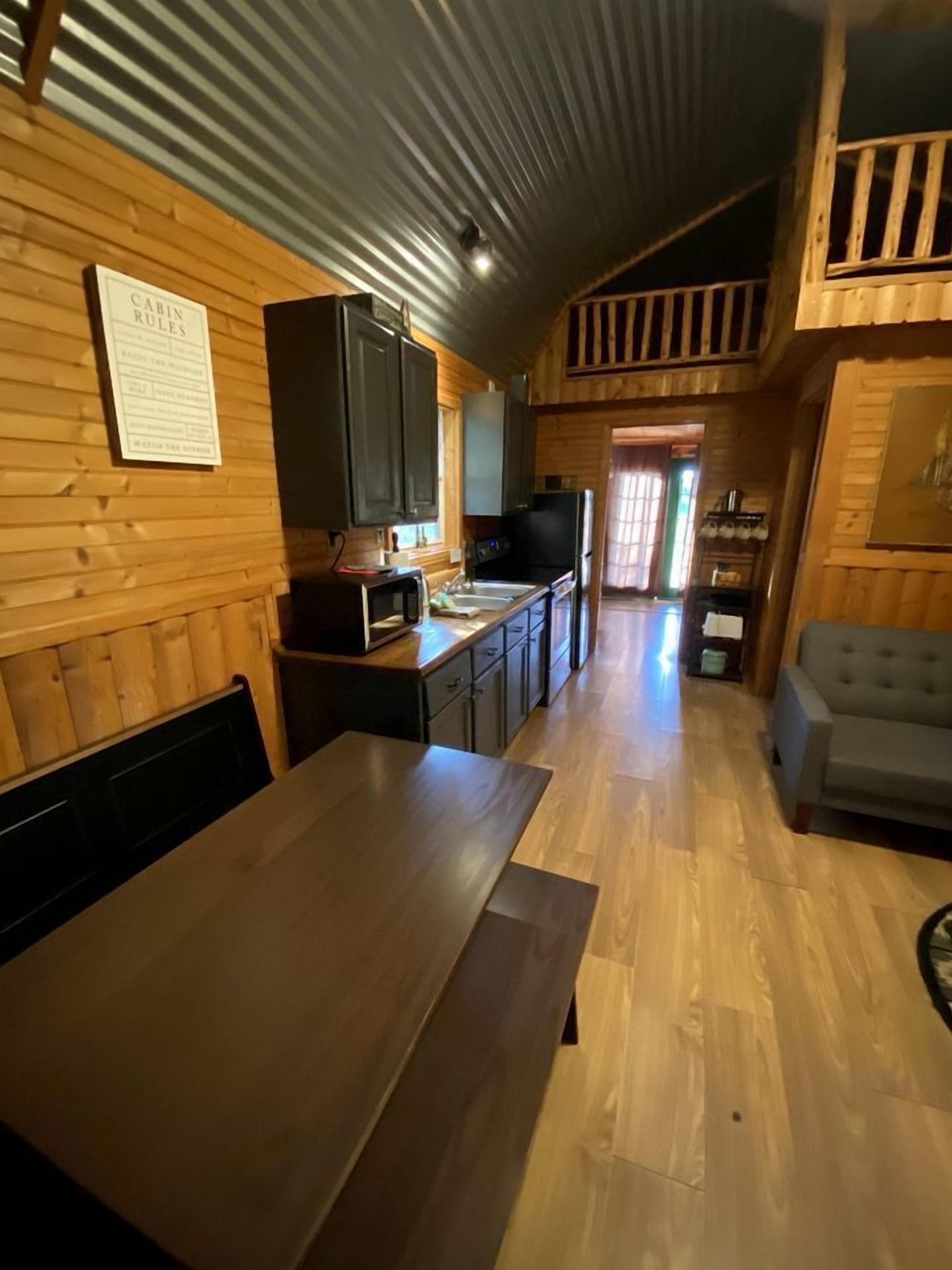 A cabin interior with a dining table, kitchen area, and a sofa.