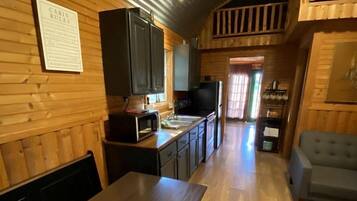 A cabin interior with a dining table, kitchen area, and a sofa.