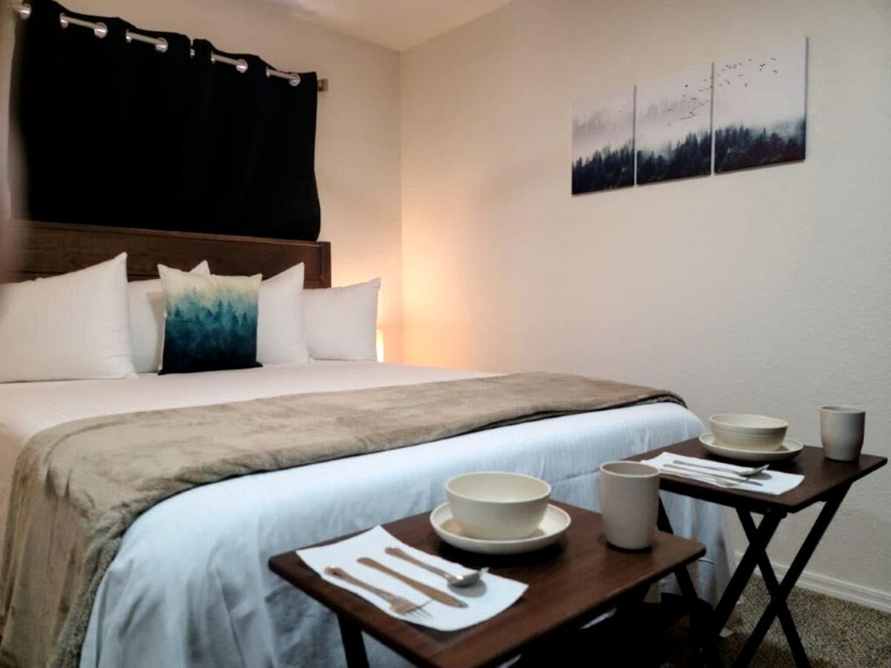 A bedroom with a bed, bedside tables, and a wall-mounted painting.