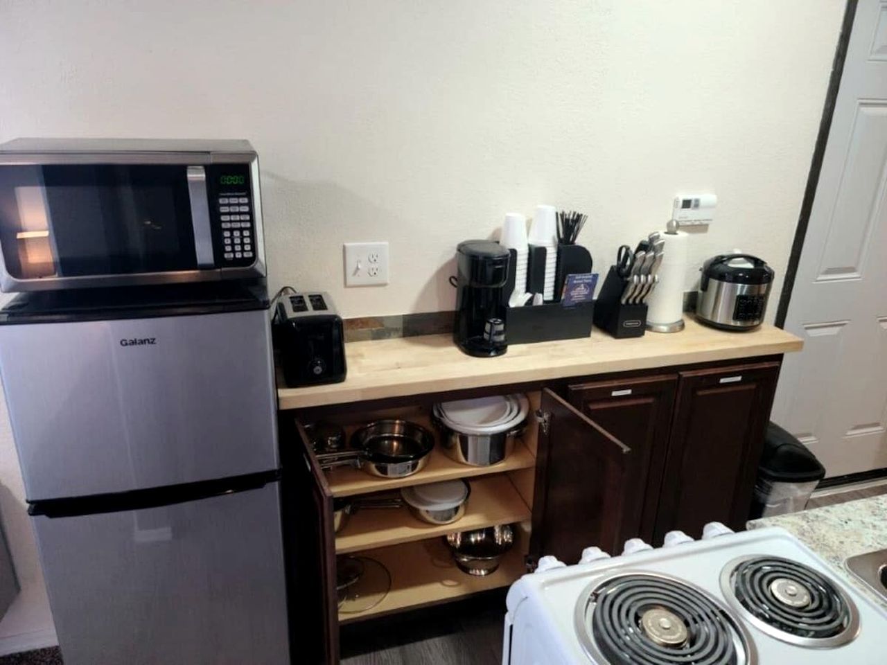 Eine kompakte Küche mit einer Galanz-Mikrowelle, einer Kaffeemaschine, einem Toaster und einem Herd.