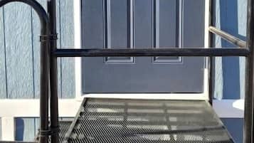 A metal bench with a metal railing in front of a blue door with the letter 'B' on it.