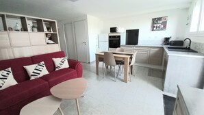 Ein kompakter Wohnbereich mit Küchenzeile, Essbereich und einem roten Sofa mit Zierkissen.