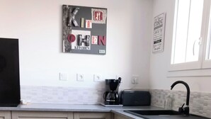 Eine moderne Küche mit Essbereich, einer Kaffeemaschine und einem Geschirrspüler.