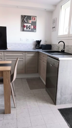 A modern kitchen with a dining area, a coffee machine, and a dishwasher. - Cosy, fully-equipped studio renovated to a high standard Amenities on foot, beach only 3 kms away (Plouhinec)