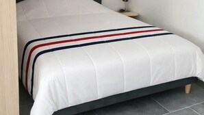 Ein modernes Schlafzimmer mit Bett, Nachttisch, Lampe und Kleiderschrank.