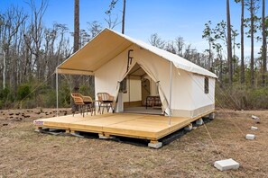 A tent with a flat roof, two chairs, and a table on a wooden platform.
