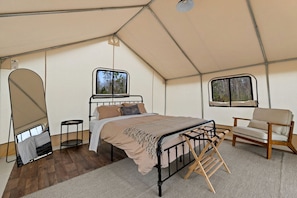 Una habitación con tienda de campaña, una cama, una silla y un ventanal.