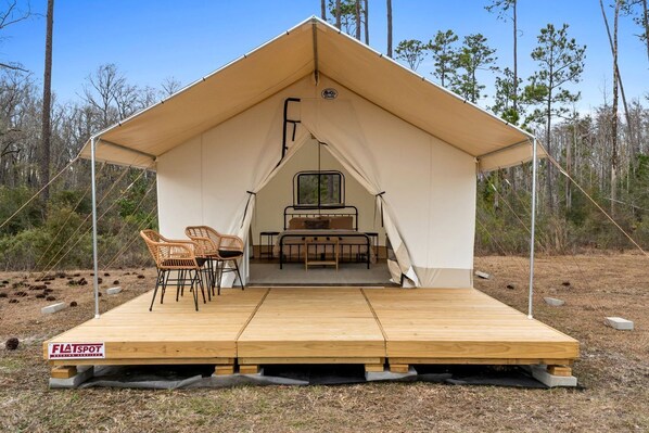 A tent with a bed, two chairs, and a window.