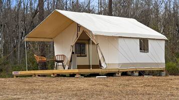 A tent with a covered porch, a chair, and a small table.