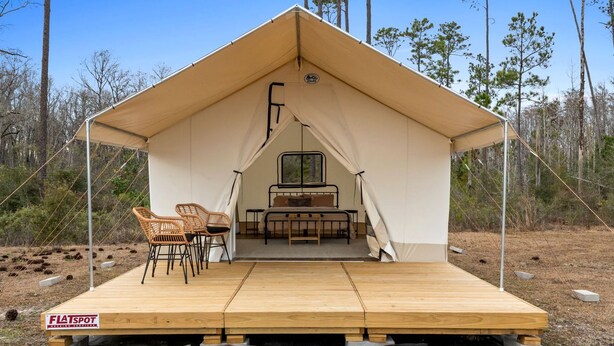 A tent with a bed, two chairs, and a window.