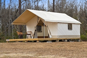 A tent with a covered porch, a chair, and a small table.