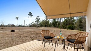 An outdoor patio with two wicker chairs, a small round table, and a bottle of liquor.