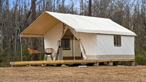 A tent with a covered porch, a chair, and a small table.