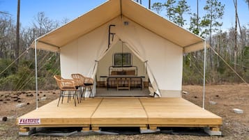 A tent with a bed, two chairs, and a window.