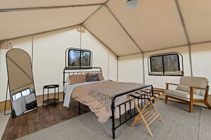 Una habitación con tienda de campaña, una cama, una silla y un ventanal.