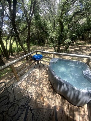 A hot tub on a wooden deck surrounded by trees. - The Renegade in Bluff Dale, TX (Bluff Dale)