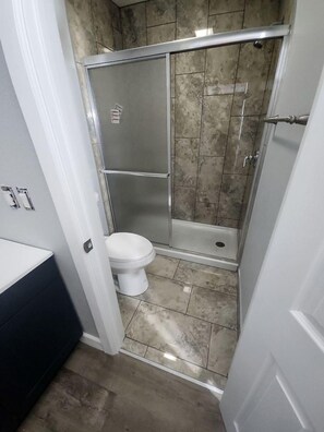 Une salle de bain avec une douche, des toilettes et un lavabo blanc.