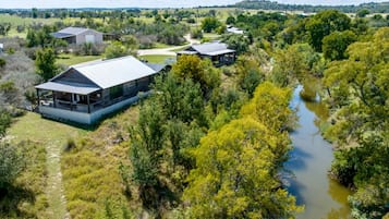 En lantlig fastighet med ett stort hus, en mindre byggnad och en flod.