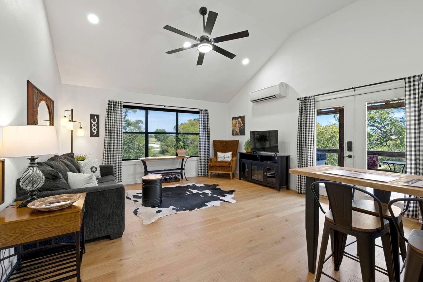 A modern living room with a sofa, a dining table, a TV, and a ceiling fan.