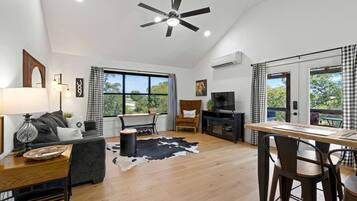 A modern living room with a sofa, a dining table, a TV, and a ceiling fan.