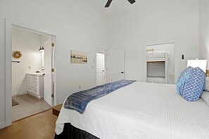 A bedroom with a bed, a dresser, a vanity, and a door leading to another room.
