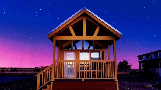 A wooden cabin with a balcony, windows, and a porch.